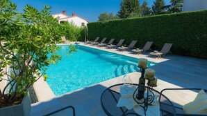 Un espace piscine avec des chaises longues et une table préparée pour les repas.