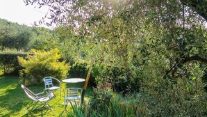Ein Garten mit Tisch und Stühlen, umgeben von üppigem Grün und verschiedenen Pflanzen.
