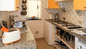 Eine kompakte Küche mit Gaskochfeld, Spüle und kleinem Kühlschrank.