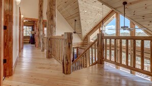 Un intérieur en bois avec un plafond haut, un escalier et de grandes fenêtres.