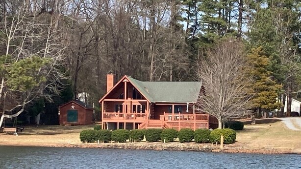 A cabin-style building with a green roof, situated by a lake.