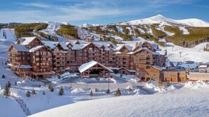 Ein großes Chalet mit mehreren Gebäuden, umgeben von schneebedeckten Bergen und einer Skipiste.