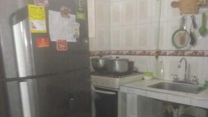 A compact kitchen with a refrigerator, stove, sink, and tiled backsplash. - Casa Wilber (Cali)