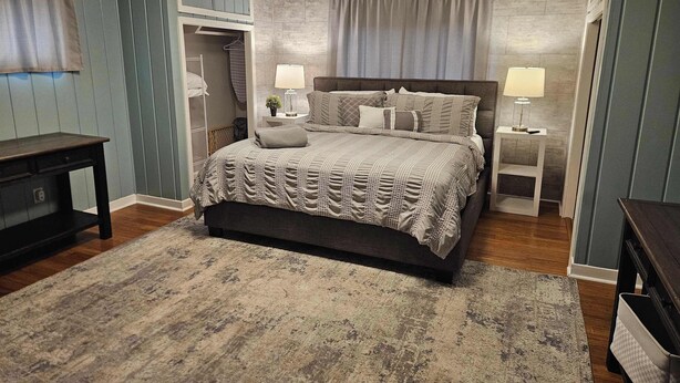 Un dormitorio con cama, mesitas de noche, cómoda y armario.