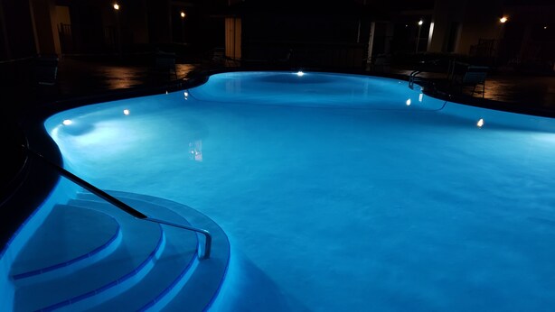 Une piscine illuminée de lumière bleue, de nuit.