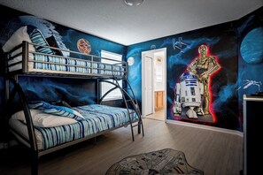 A room with a bunk bed, a Star Wars-themed mural, and a Star Wars poster on the wall.