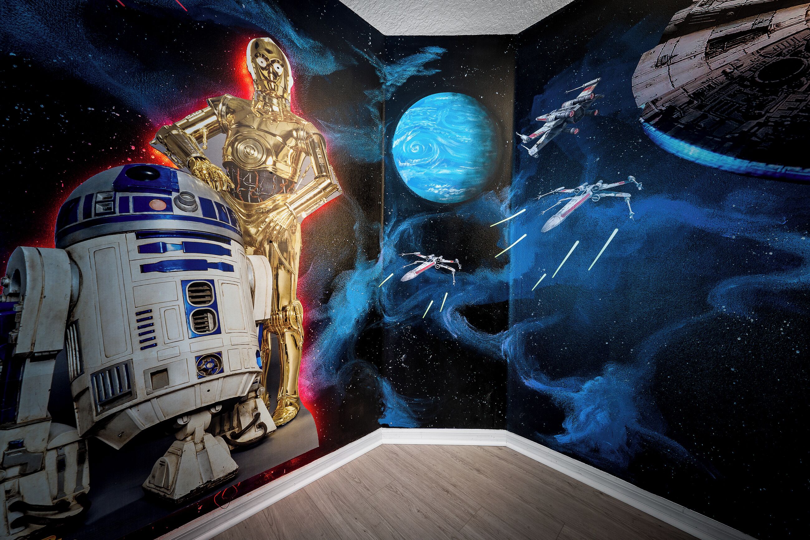 A room with a space-themed mural including a golden robot, a blue and white droid, and a planet.