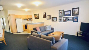 A compact living space with a kitchenette, grey sofa, and a flat-screen TV. - Prime Location | North Adelaide 2BR Apt, Melbourne St | Courtyard |Near CBD Events + Private Parking (North Adelaide)