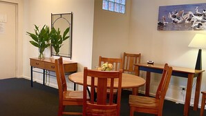 A dining area with a round table, wooden chairs, a small plant on a side table, and a painting on the wall. - Prime Location | North Adelaide 2BR Apt, Melbourne St | Courtyard |Near CBD Events + Private Parking (North Adelaide)
