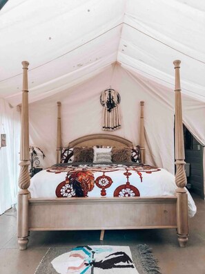 Un lit à baldaquin avec une couvre-lit à motifs, un luminaire suspendu et un tapis sur le sol.