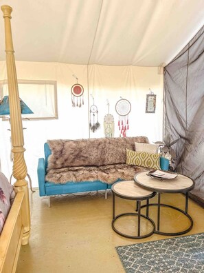 Una habitación acogedora con un sofá azul, una mesa redonda y una cama con cabecero de madera.