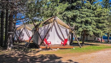 En campingplats med två tält, där varje tält har en upphöjd yta och röda stolar.