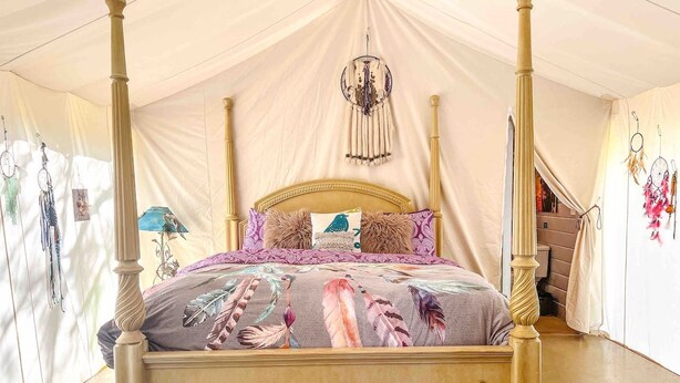 A four-poster bed with a floral bedspread, a chandelier, and wall art.