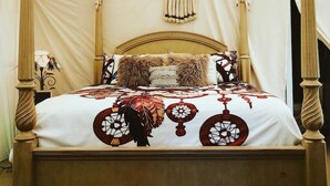 A four-poster bed with a white canopy tent, a patterned bedspread, and a wall-mounted decorative item.