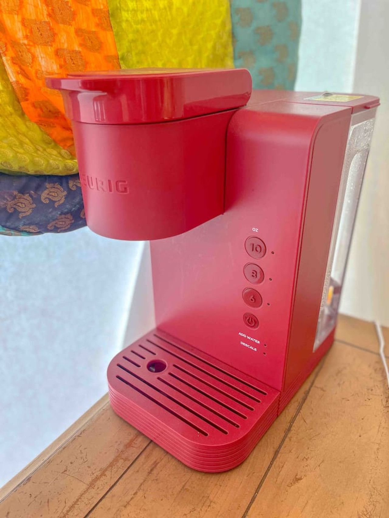 Una cafetera roja con panel de control, sobre una superficie de madera.