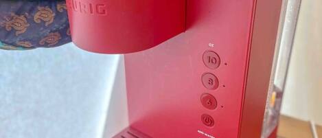 Una cafetera roja con panel de control, sobre una superficie de madera.