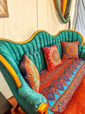 A teal upholstered sofa with patterned cushions and a matching ottoman, set against a plain wall. - Arabian nights Luxury suite, Glamping tent (Irwin)