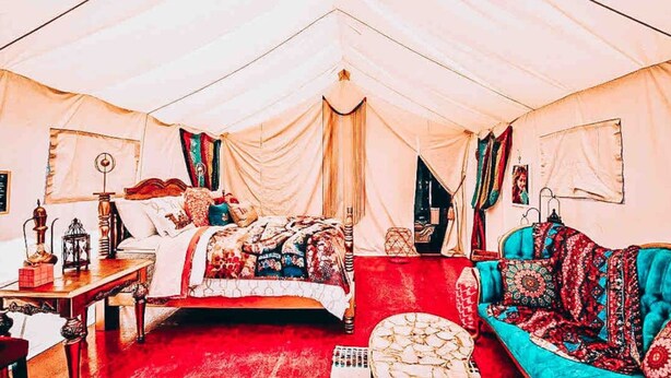 A tented room with a bed, a sofa, and a table. - Arabian nights Luxury suite, Glamping tent (Irwin)