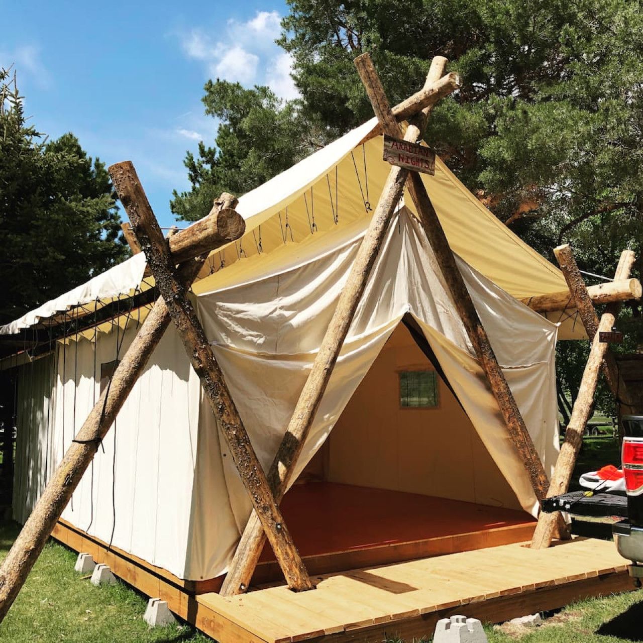 A tent with a simple, functional design, featuring a canvas interior and a wooden frame structure.