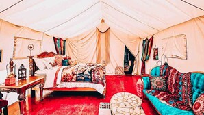 A tented room with a bed, a sofa, a table, and a lamp. - Arabian nights Luxury suite, Glamping tent (Irwin)