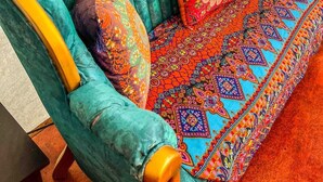 A teal upholstered sofa with patterned cushions and a matching ottoman, set against a plain wall. - Arabian nights Luxury suite, Glamping tent (Irwin)