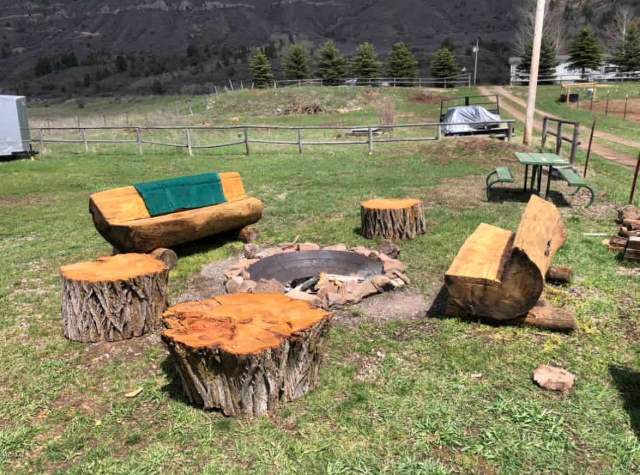 Zona d'estar a l'exterior de disseny rústic, amb una xemeneia, seients de fusta i un banc cobert.