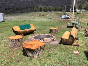 Zona d'estar a l'exterior de disseny rústic, amb una xemeneia, seients de fusta i un banc cobert.