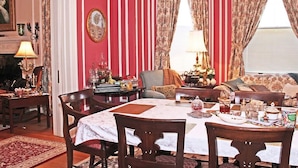 A dining room with a table set for four, surrounded by chairs, a fireplace, and a sofa. - Port City Guest House (Wilmington)