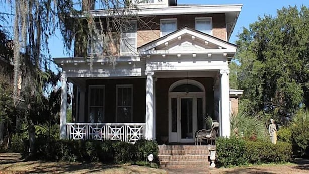 A two-story house with a front porch, a central entrance, and a small garden area. - Port City Guest House (Wilmington)