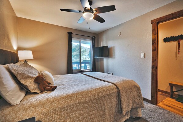 A bedroom with a bed, a ceiling fan, a window, a television, and a teddy bear. - Mountain Views! Hot Tub/Pool Walk to Lifts & Main1 (Park City)