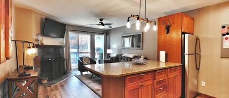 A kitchen with wooden cabinets, a granite countertop, a built-in refrigerator, and a ceiling fan.