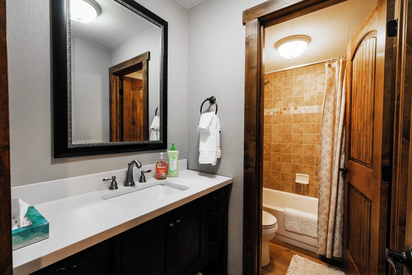 A bathroom with a white sink, a mirror, a shower curtain, and a toilet.