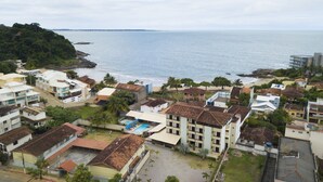 A coastal residential area with buildings, a beach, and a view of the sea. - Coqueiros Praia Hotel - Balneário de Iriri (Anchieta)