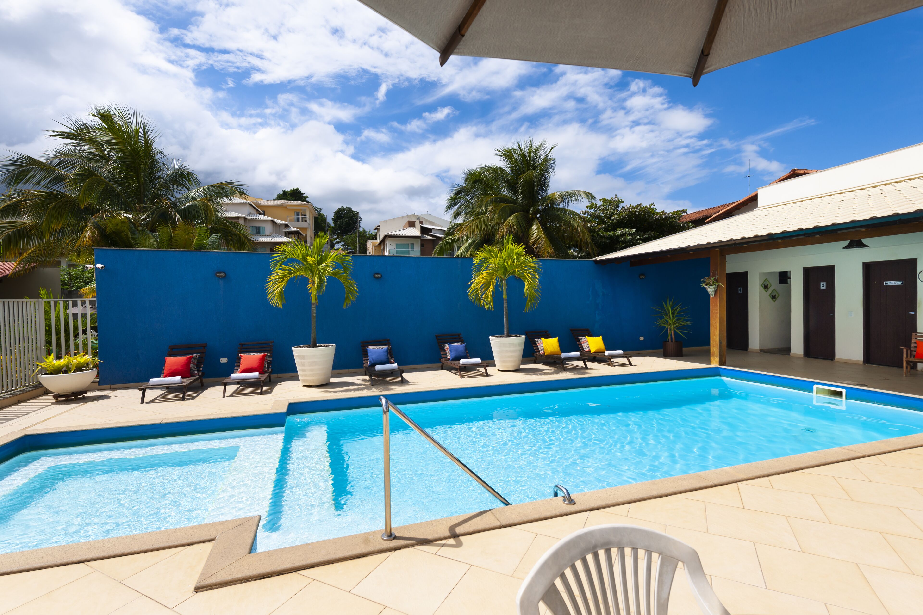 A swimming pool with lounge chairs and palm trees.