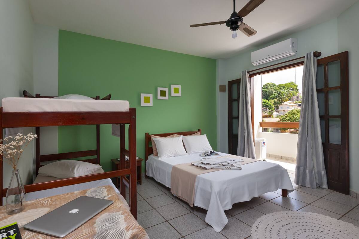 A room with bunk beds, a desk with a laptop, and a bed with a white bedspread.