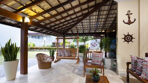 A covered outdoor seating area with wooden furniture, potted plants, and nautical decor. - Coqueiros Praia Hotel - Balneário de Iriri (Anchieta)