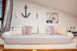 A cozy room with a sofa bed, a wall-mounted phone, an anchor decoration, and a record player.