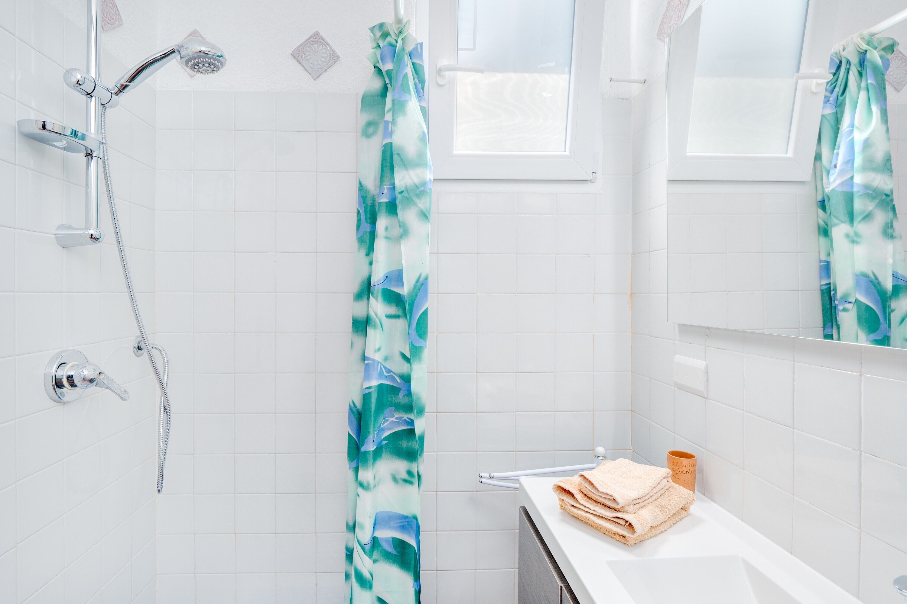Une salle de bain avec une douche, un lavabo avec des serviettes et un miroir.