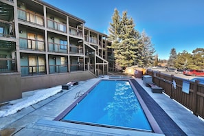 A multi-story building with a swimming pool, outdoor seating, and a fenced area. - First Chair Snowcrest Base Camp | Walk to Lifts (Park City)