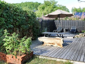 A wooden deck with a barbecue area, a patio umbrella, and outdoor furniture.