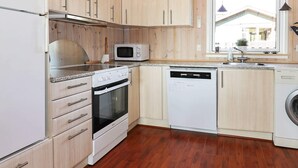 A kitchen with wooden cabinets, a microwave, an oven, and a dishwasher. - Cozy Holiday Home in Hadsund near Sea (Hadsund)