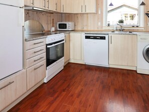 A kitchen with wooden cabinets, a microwave, an oven, a dishwasher, and a washing machine.