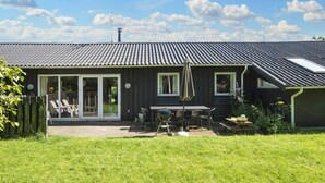 A house with a dark exterior, a tiled roof, and a covered patio area with outdoor furniture.