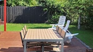 Une terrasse en bois avec une table et quatre chaises.