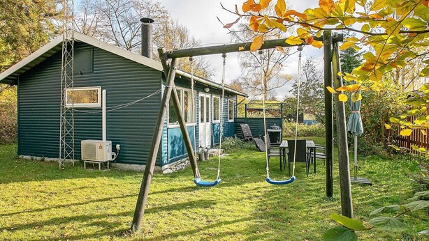 A backyard with a swing set, a small shed, and a table with chairs.