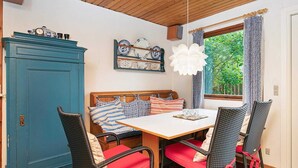 A dining area with a wooden table, chairs, a blue cabinet, and a window with curtains.