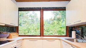 A kitchen with white cabinets, a large window, and a Bosch dishwasher.