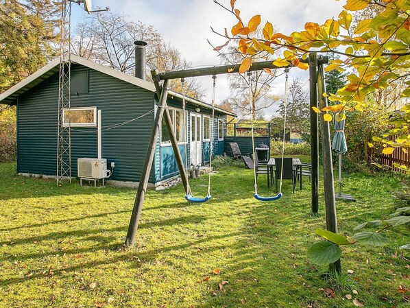 A backyard with a swing set, a small shed, and a patio table.