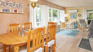 A wooden dining table with six chairs, a chandelier, and a window with curtains. - 7 Person Holiday Home in Jerup (Strandby)