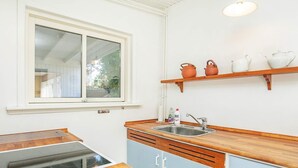 A compact kitchen with a window, a sink, a wooden countertop, and a built-in stove. - 7 Person Holiday Home in Jerup (Strandby)